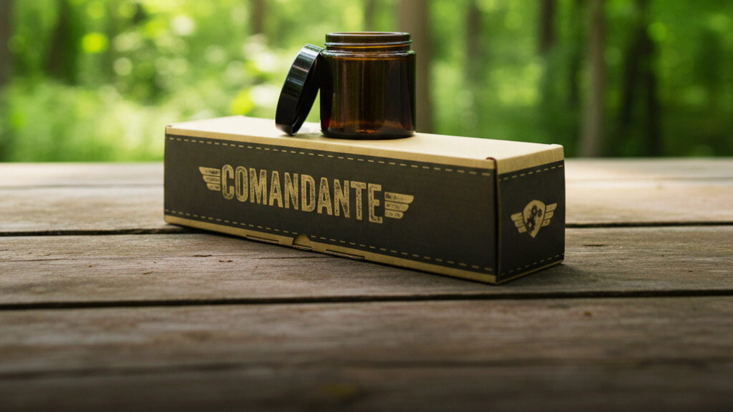 Comandante Handkaffeemühle draußen auf einer Holzplatte in der OVP liegend. Darauf ist ein Comandante Bean Jar, braun, platziert