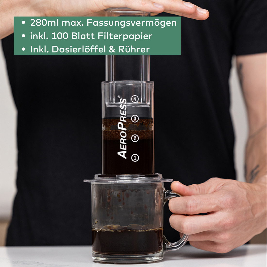 AeroPress clear, auf einem Becher stehend und wird gerade gepresst